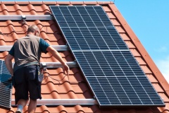 Two men installing new solar panels on the roof of a private house. Renewable energy concept and green energy abstract.